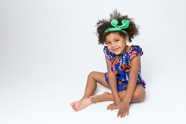 Alegre niño afroamericano en vestido azul y naranja