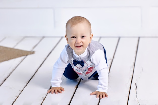 Alegre niño blanco se arrastra por el piso en el salón