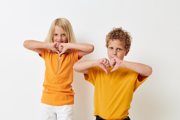 Alegre niño y niña en camisetas amarillas posando estudio