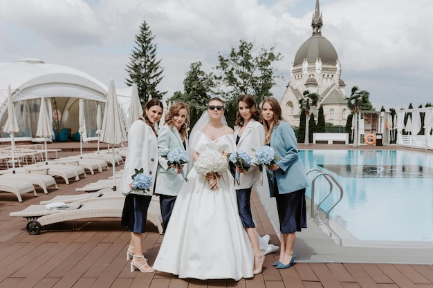 Alegre noiva e damas de honra com buquês posando ao ar livre