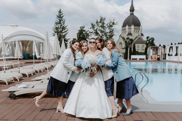 Alegre novia y damas de honor con ramos posando al aire libre