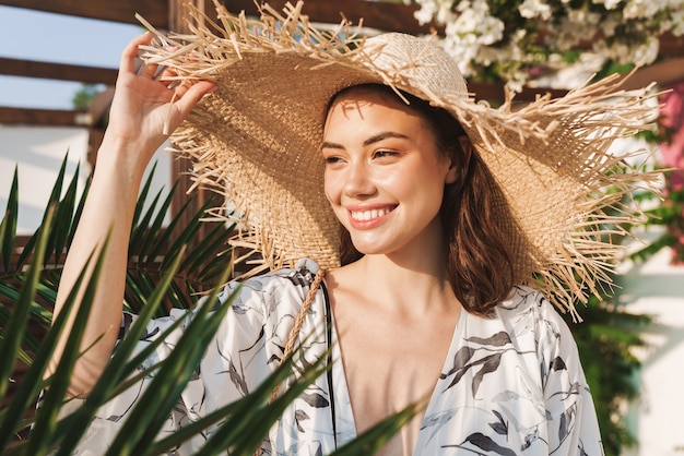 alegre otimista feliz jovem bonita na praia caminhando em uma bela manhã ensolarada sobre plantas tropicais.