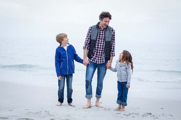 Alegre padre con hijos en la orilla del mar