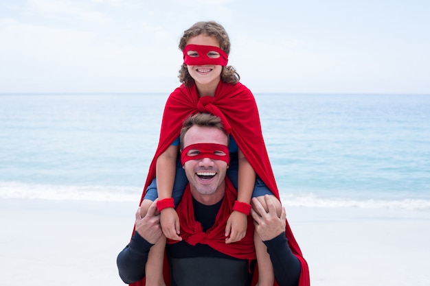 Alegre pai e filho em traje de super-heróis, desfrutando na praia