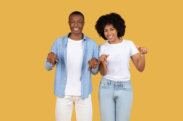 Una alegre pareja afroamericana señalando hacia abajo a una bandera blanca en blanco