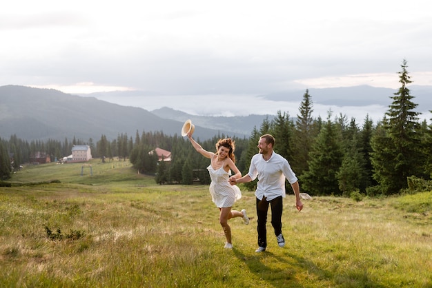 La alegre pareja corre por el claro, en el bosque y las montañas.