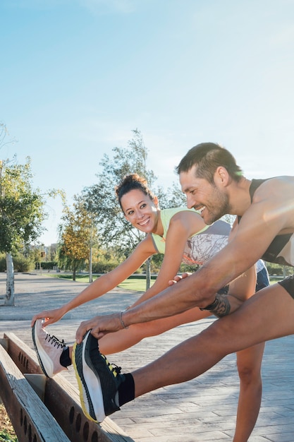 Alegre pareja de corredores estirando juntos en el parque