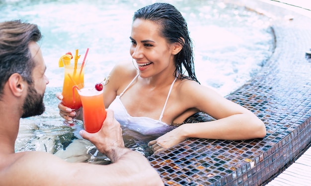 Alegre pareja de enamorados descansa en una piscina durante las vacaciones de verano.