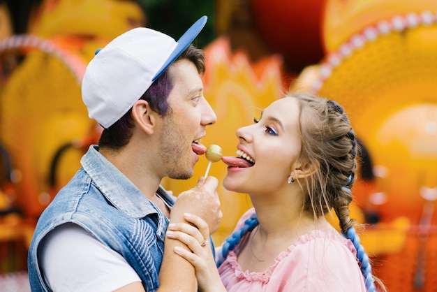 Foto alegre pareja feliz comiendo dulces en un palo