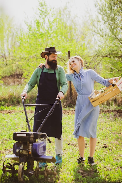 Alegre pareja de granjeros de pie en la huerta esposa y esposo pasan tiempo en el huerto