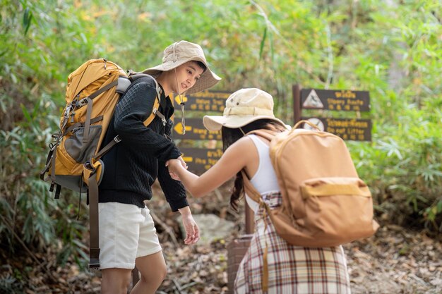 Alegre pareja de lesbianas románticas viajeras con mochila en la espalda van de excursión por el bosque en las montañas en verano