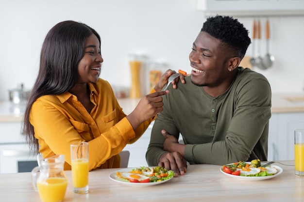 Alegre pareja negra engañando mientras desayunamos juntos en la cocina