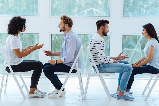 Alegre pareja positiva encantada hablando y escuchándose mientras realiza una actividad psicológica