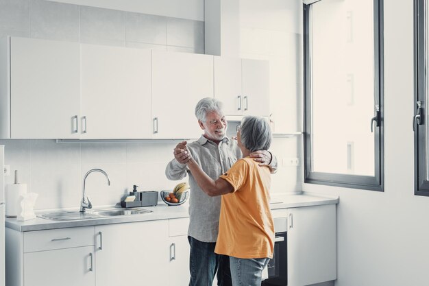 Alegre pareja romántica jubilada activa bailando riéndose en la sala de estar feliz esposa de mediana edad y esposo mayor divirtiéndose en casa sonriendo abuelos de la familia senior relajándose uniendo juntosxA