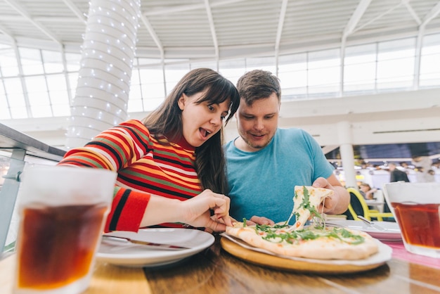 Alegre pareja sentada en el café comiendo pizza hungría