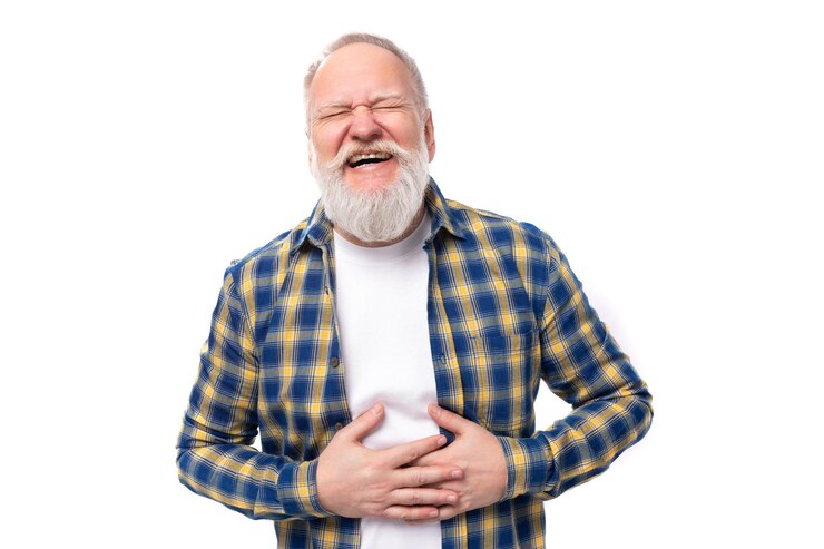 Foto alegre pensionista sênior de cabelos grisalhos com barba em uma camisa ri sobre um fundo branco com