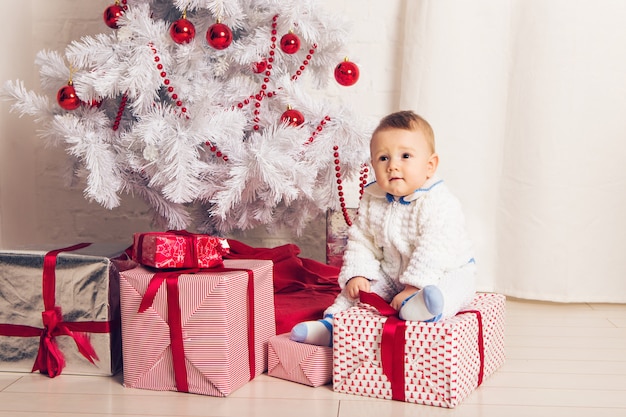 Alegre pequeño bebé jugando cerca del árbol de Navidad