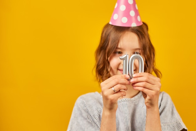 Alegre positiva diez años cumpleañera en gorro de fiesta