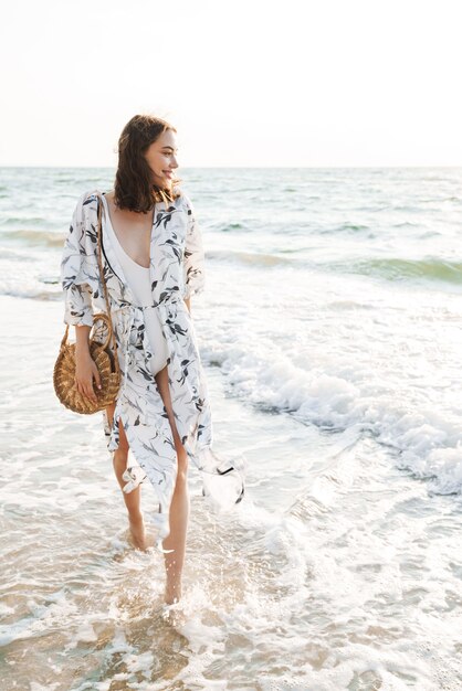 alegre positiva feliz jovem bonita na praia caminhando em uma bela manhã ensolarada.