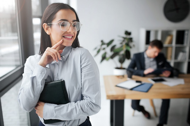 Foto alegre y positiva mujer joven de pie y sonríe