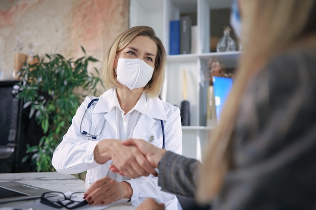 Una alegre psicóloga médica estrechando las manos agradecidas de los pacientes después de una reunión de consulta.