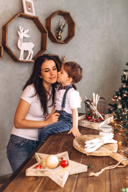 Alegre retrato de Navidad de feliz madre e hijo con regalos de año nuevo y Nochebuena con decoración de celebración y luces de Navidad