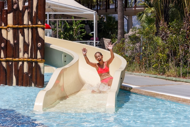 Alegre, rir, menina adolescente, abaixe, por, corrediça água, em, a, hotel, aquapark