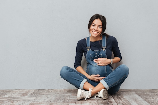 Alegre senhora grávida sentada no chão