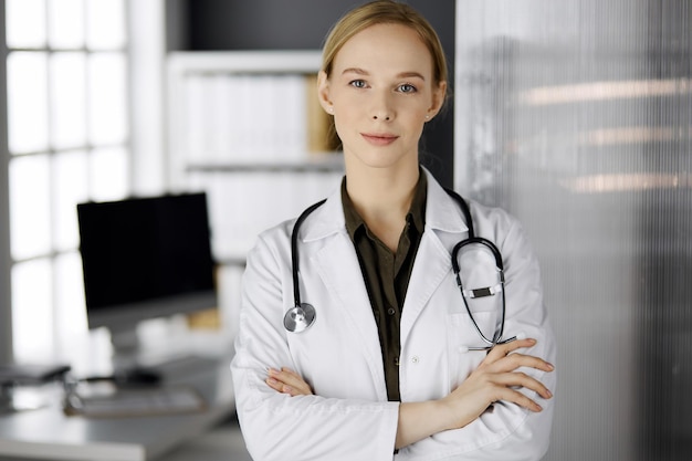 Alegre sonriente doctora de pie en la clínica. Retrato de mujer médico amable. Perfecto servicio médico en el hospital. concepto de medicina.