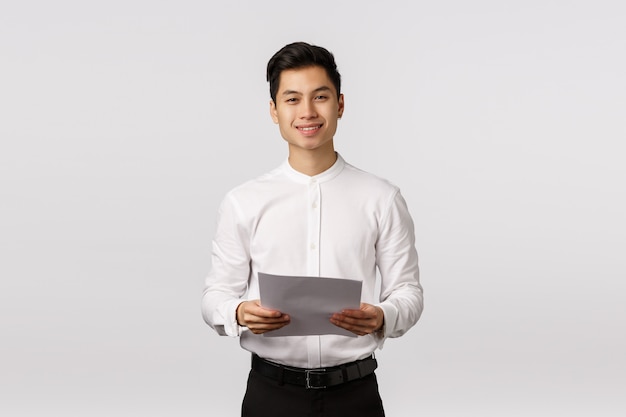 Foto alegre sorridente jovem empresário asiático com camisa branca segurando documentos