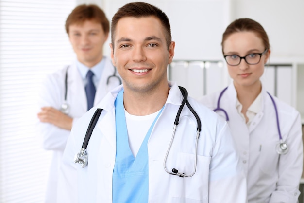 Alegre sorridente médico masculino com equipe médica no hospital