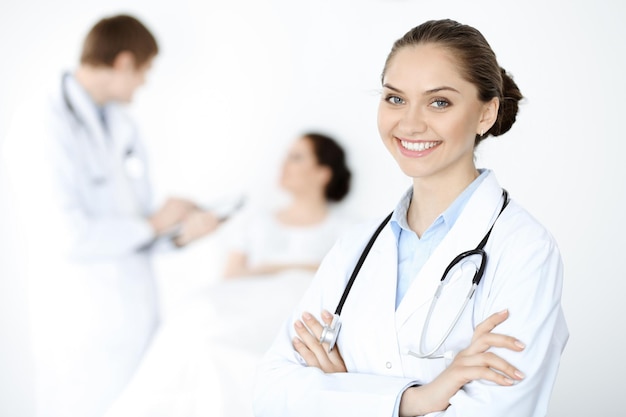 Alegre sorridente mulher-médica no fundo de seu paciente na cama. Conceito de medicina