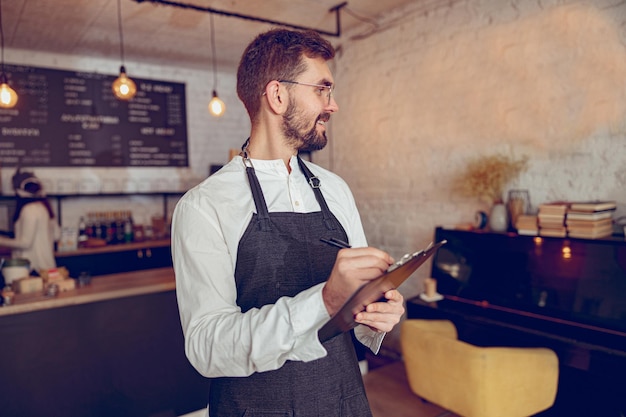 Alegre trabalhador masculino escrevendo na área de transferência no café