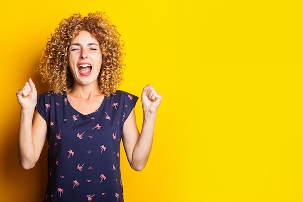 Alegremente grita jovem com os punhos fechados cerrados no fundo amarelo