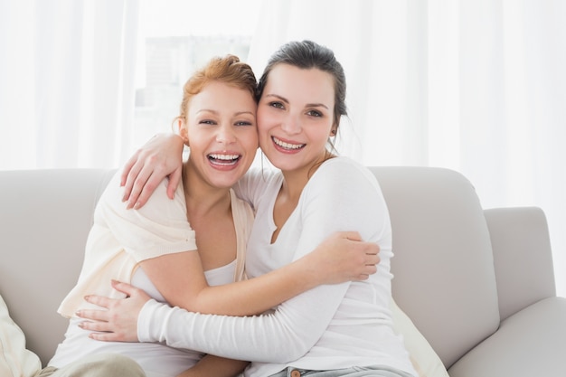 Alegres amigas abrazándose en la sala de estar