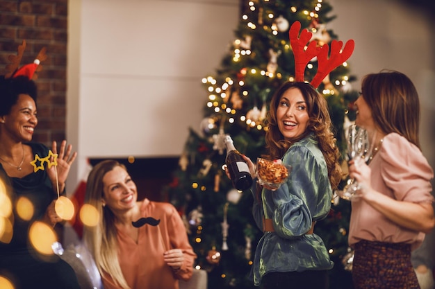 Alegres amigas multiétnicas divirtiéndose mientras brindan con champán en Navidad o en la fiesta de Año Nuevo juntas.