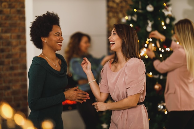 Alegres amigas multiétnicas pasando un buen rato juntas en la fiesta de Nochevieja en un ambiente festivo.