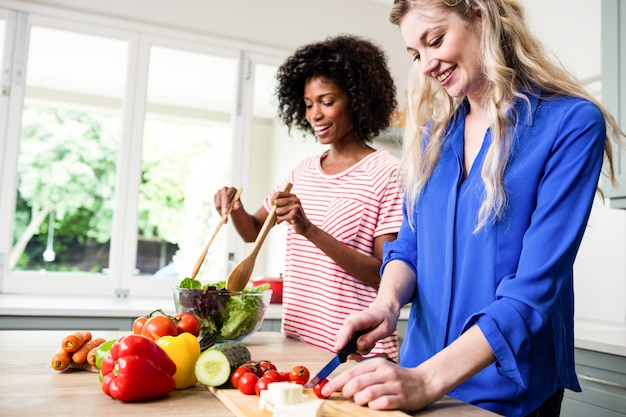 Alegres amigas preparando comida na mesa