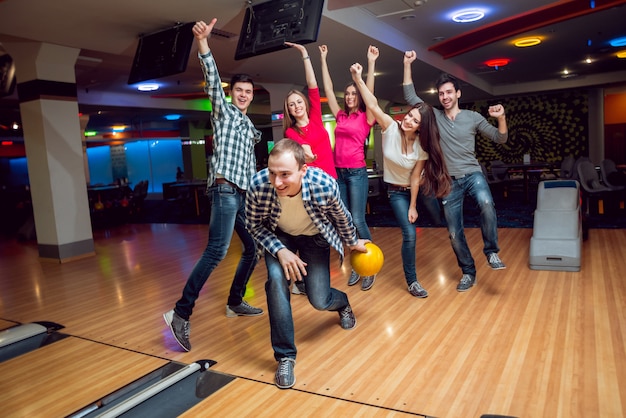 Foto alegres amigos en la bolera con las bolas.