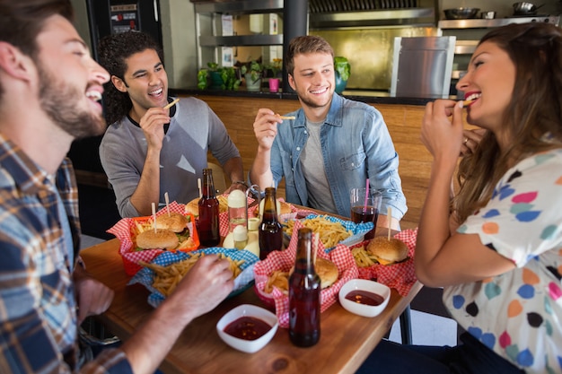 Alegres amigos comiendo papas fritas en el restaurante