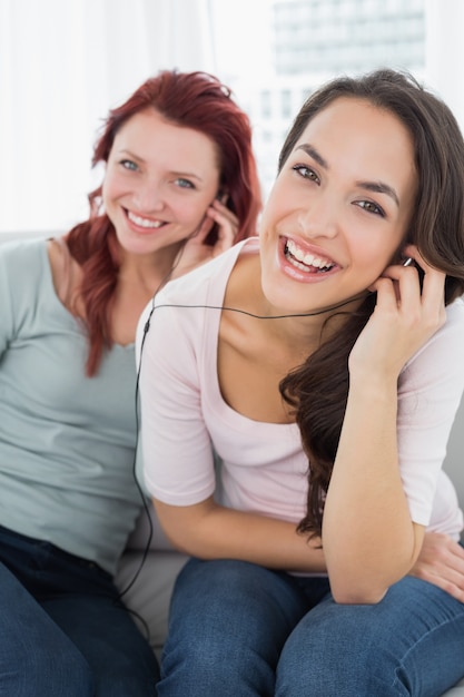 Alegres amigos escuchando música a través de auriculares juntos