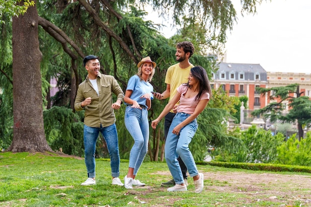 Alegres amigos multiculturales bailando al son de la música en el colorido parque de la ciudad