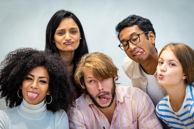 Alegres amigos multirraciales haciendo un selfie sacando la lengua y haciendo muecas feliz grupo de estudiantes de todas partes del mundo divirtiéndose mirando el concepto de cámara de la diversidad de personas