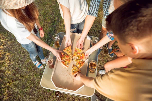 Alegres amigos no piquenique no parque. Comendo pizza