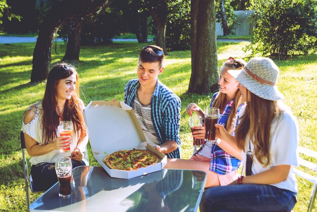 Alegres amigos de picnic en el parque. Comiendo pizza