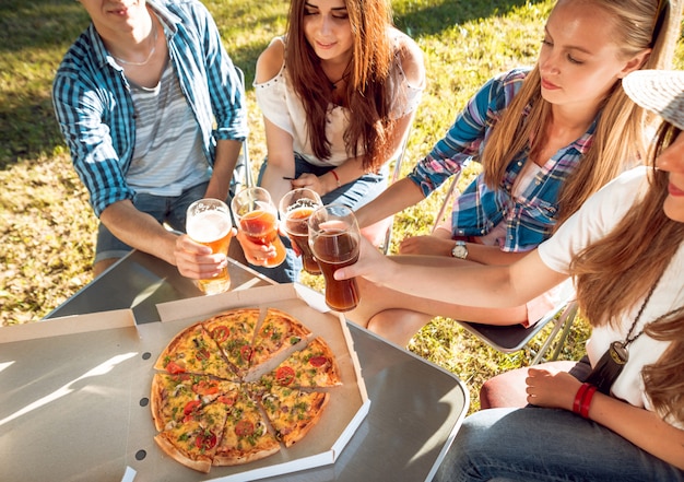 Alegres amigos de picnic en el parque. Comiendo pizza