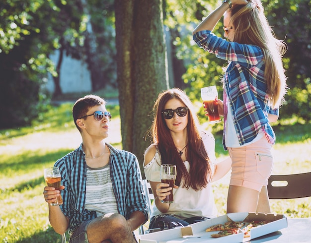 Alegres amigos de picnic en el parque. Comiendo pizza