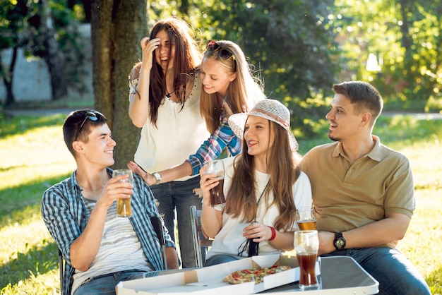 Alegres amigos de picnic en el parque. Comiendo pizza