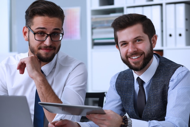 Alegres compañeros de trabajo con tableta en el trabajo