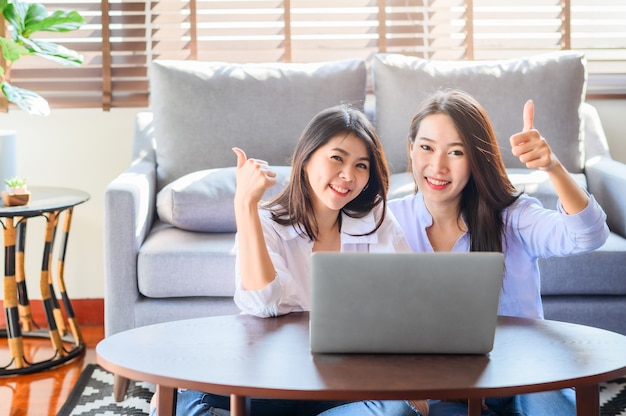 Alegres fêmeas asiáticas usando um laptop juntos